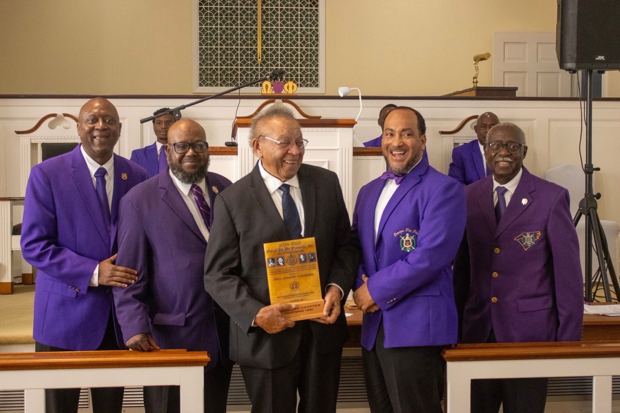 Johnny Gardner holding the Founders’ Lifetime Achievement Award with Delta Rho Chapter members